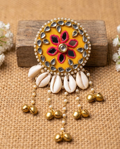 Handmade Kanak mustard mirror hair brooch with pink thread floral work and cowrie shells