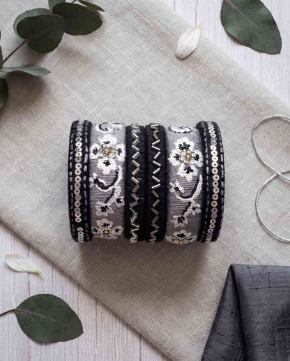Black and grey silk thread bangles styled with eucalyptus leaves and white petals