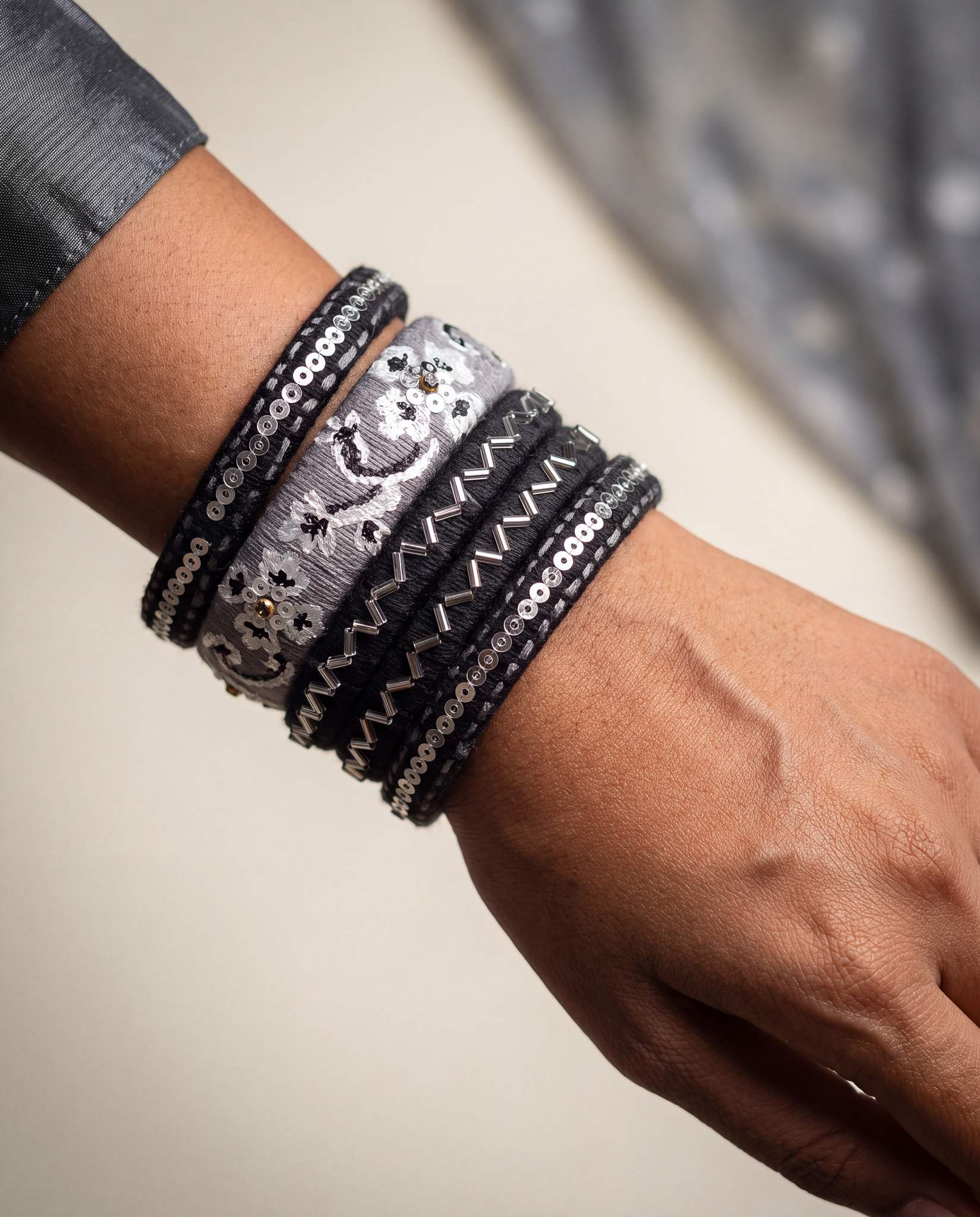 Woman wearing black and grey silk thread bangles stacked on wrist