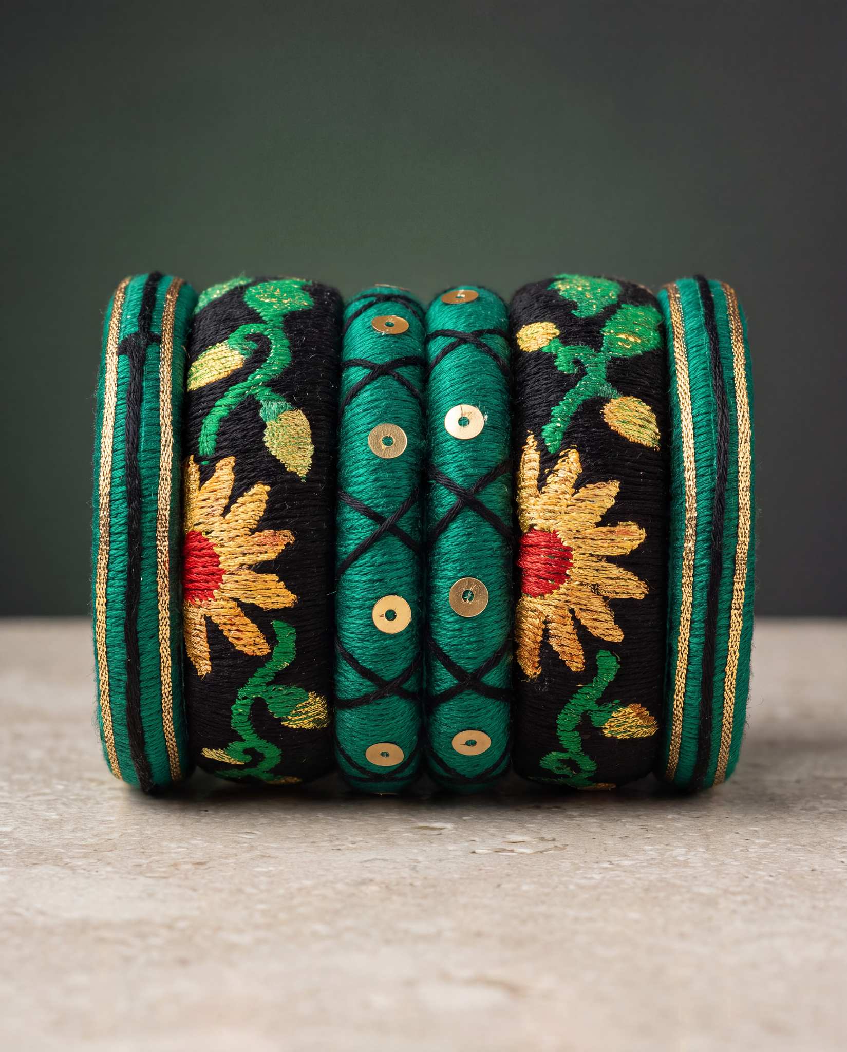 Close-up of green silk thread bangles with gold sequin detailing and sunflower embroidery