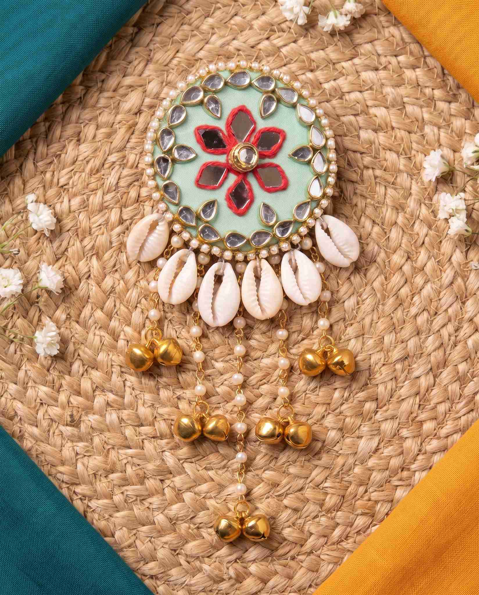 Mint green mirror hair brooch styled on jute mat with teal and mustard fabric corners