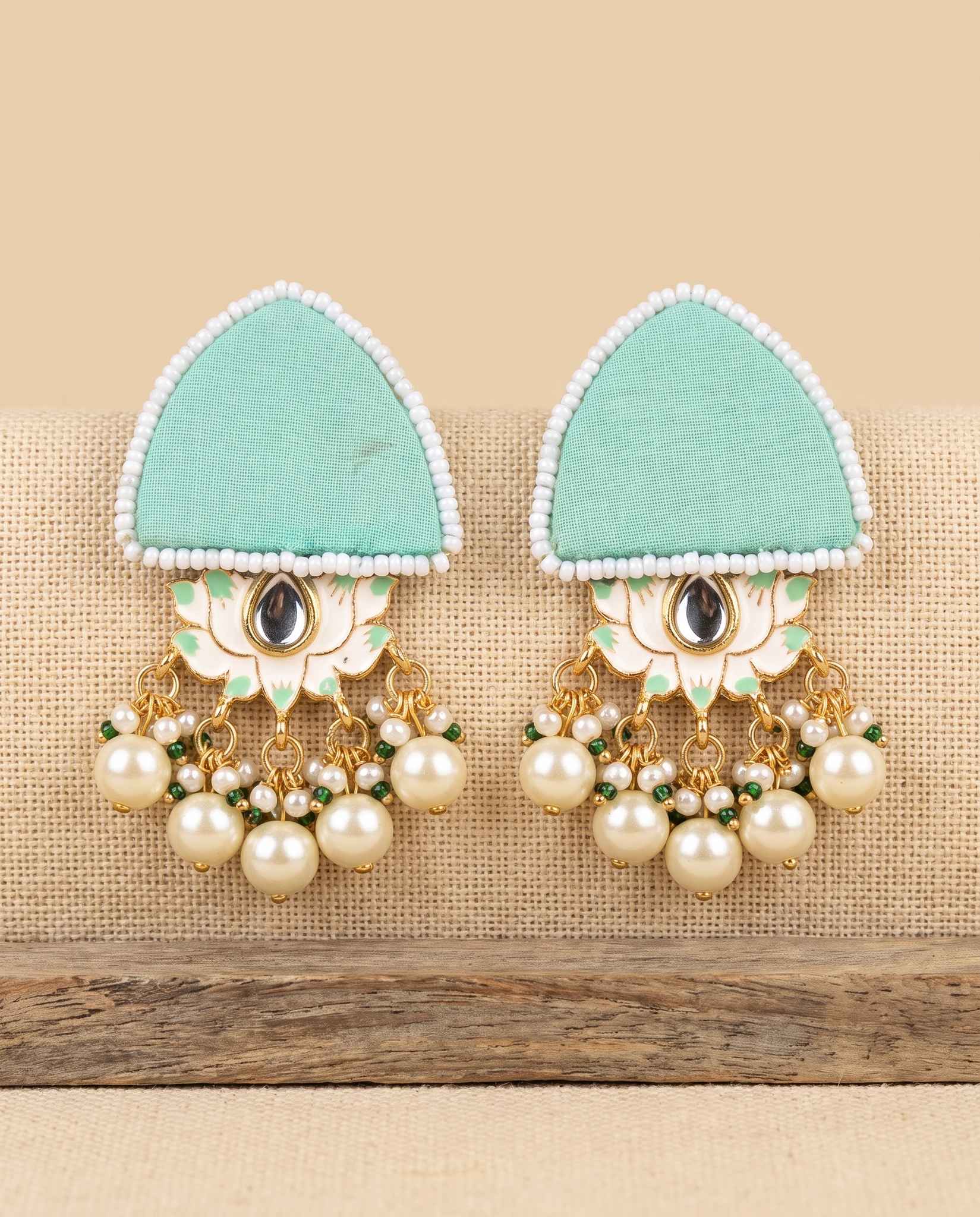 Mint green fabric floral earrings with pearl tassels on jute weave background