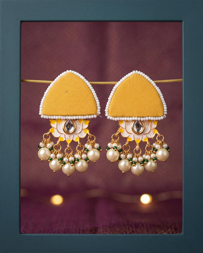 Mustard yellow pearl floral earrings displayed in teal frame with fairy lights