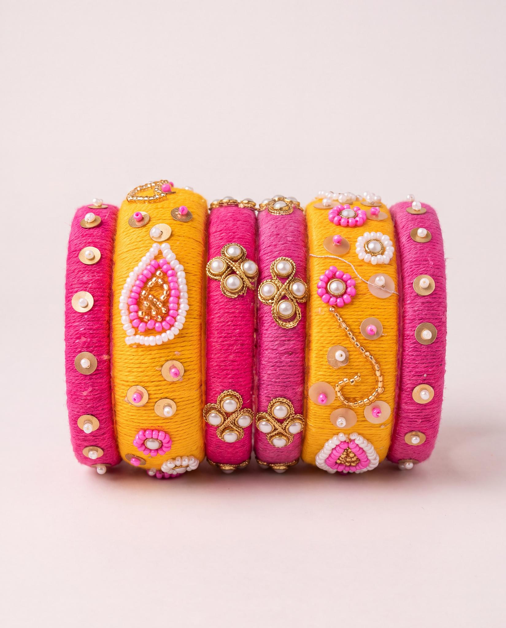 Pink and mustard silk thread bangle set with pearl and beadwork floral detailing on plain background