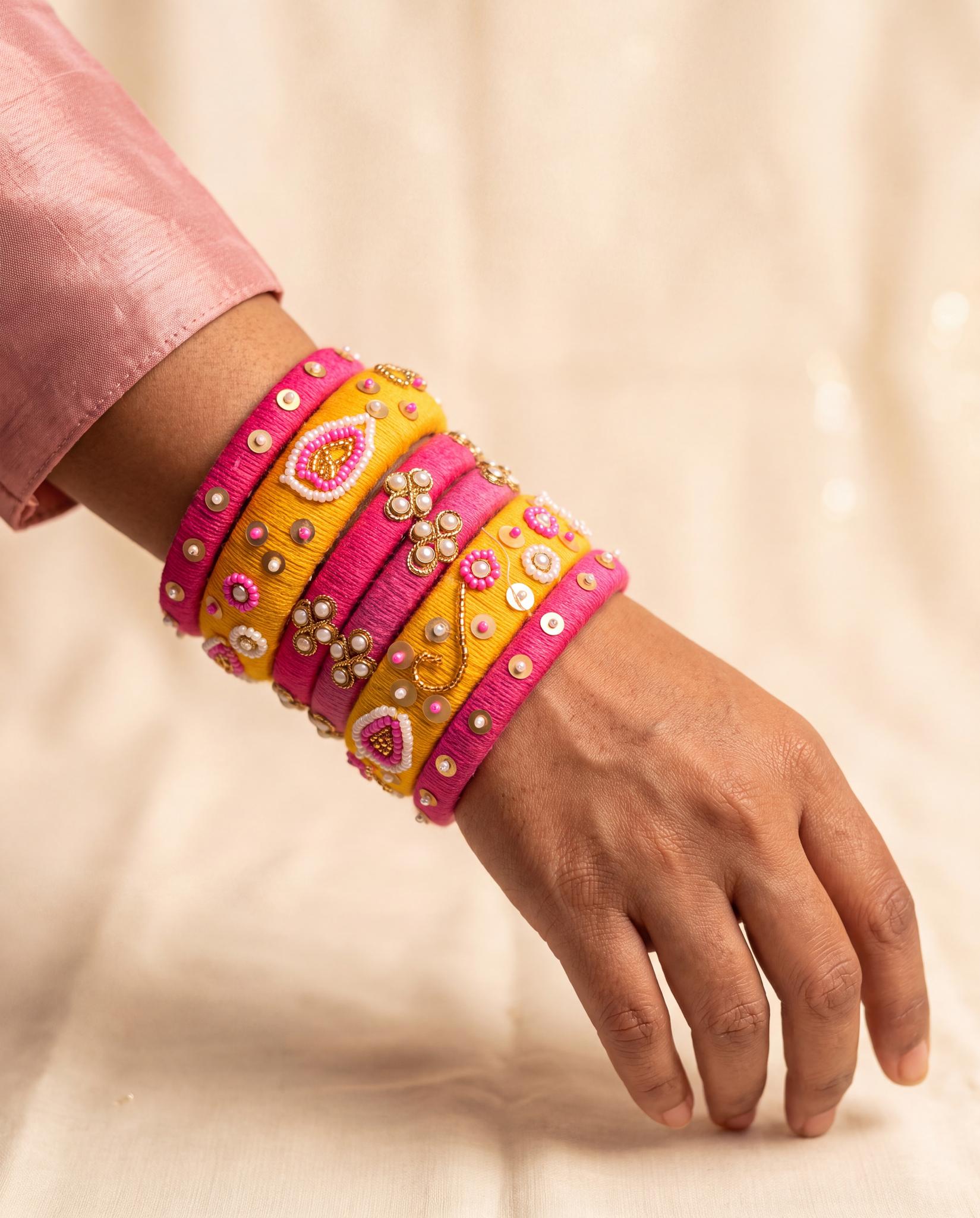 Woman wearing pink and mustard floral beadwork silk thread bangles stacked on wrist
