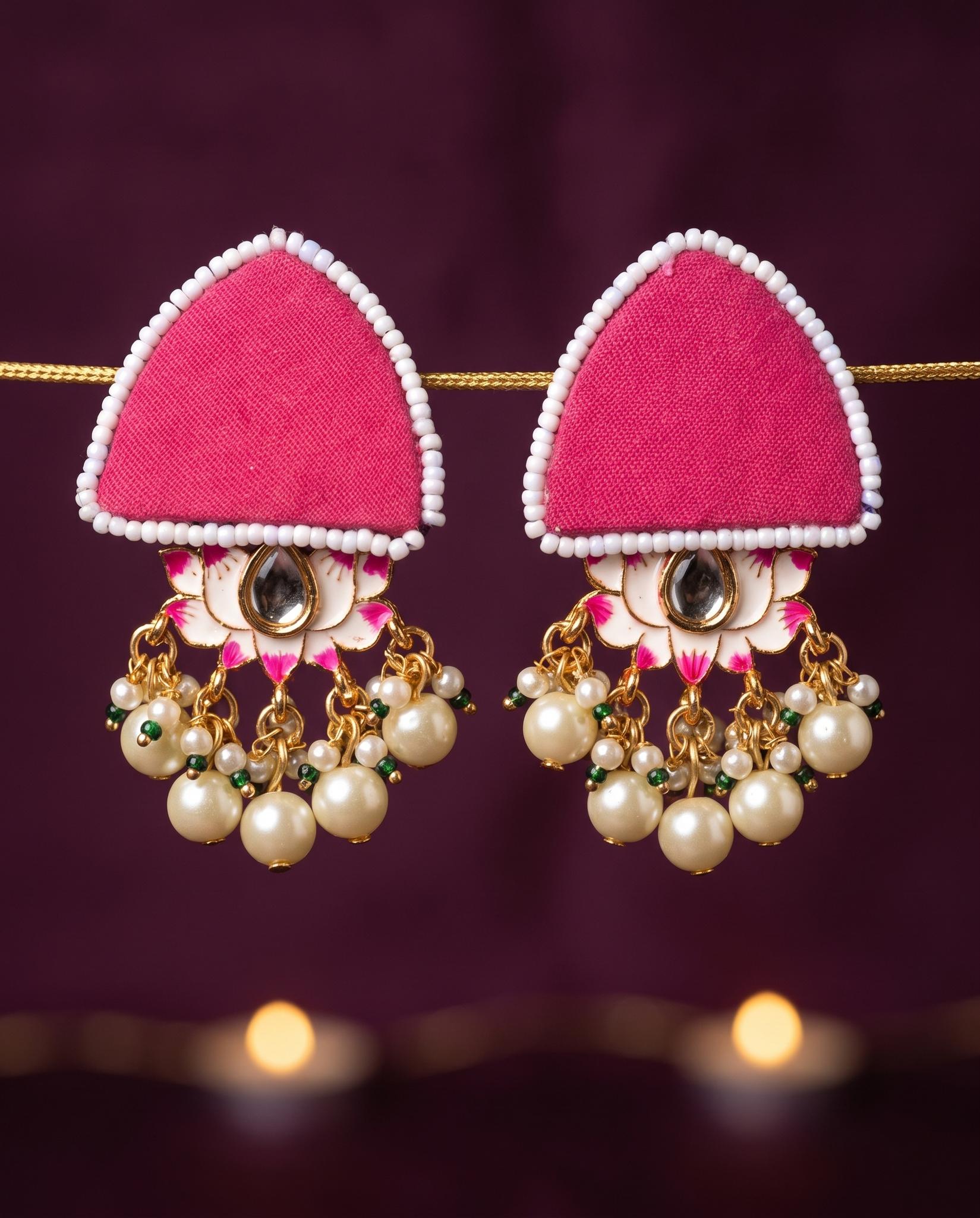 Pink pearl floral earrings displayed against dark plum backdrop with candlelight