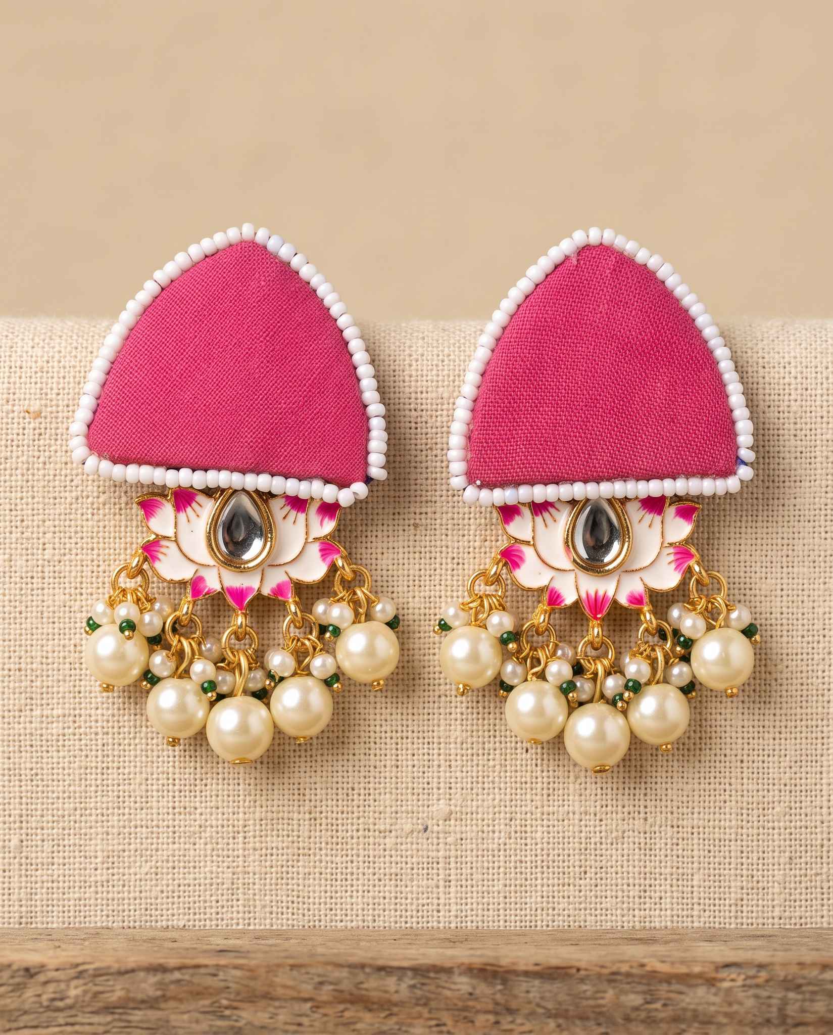 Pink fabric floral earrings with pearl tassels on jute weave background