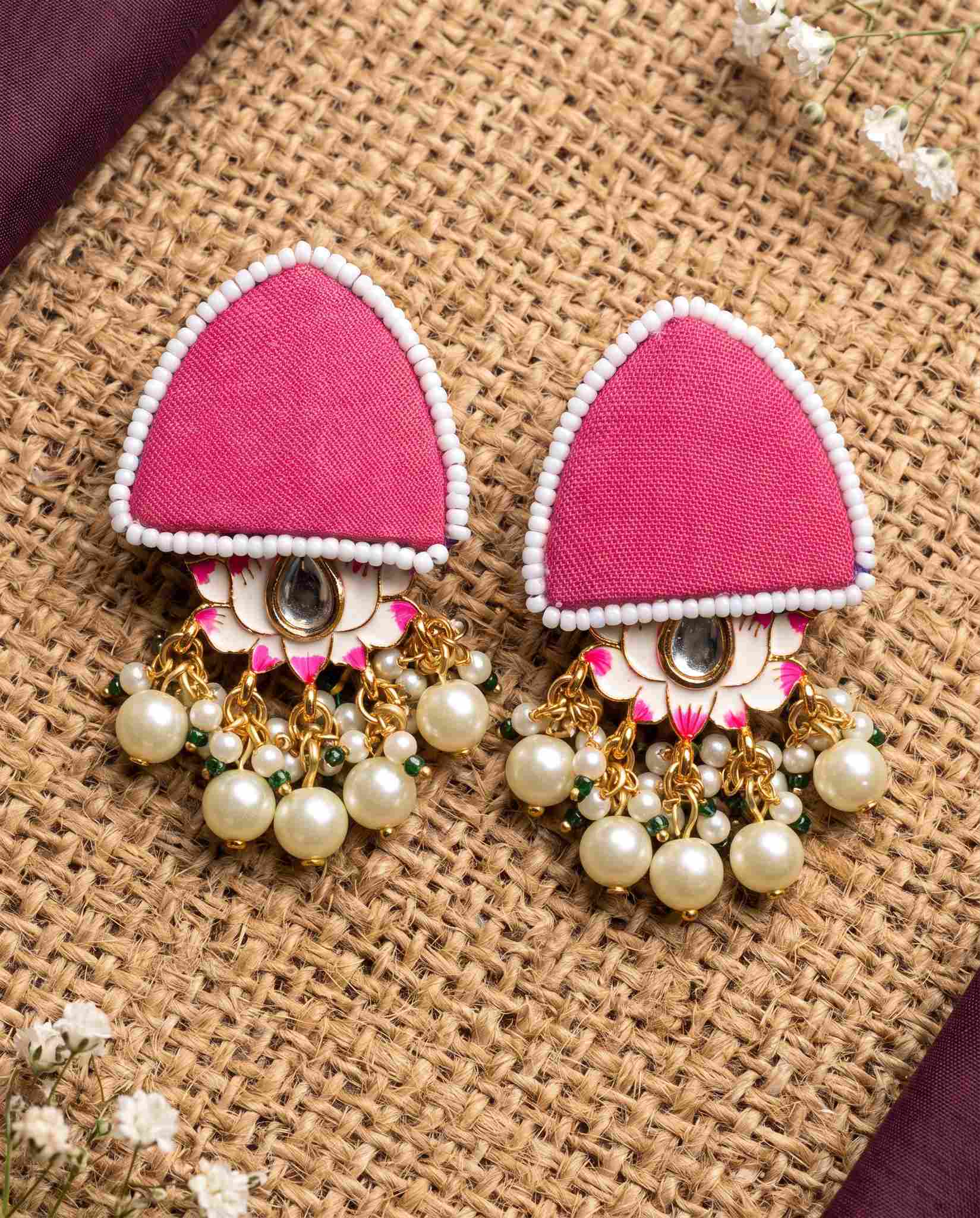 Pink pearl floral earrings styled on jute mat with plum fabric