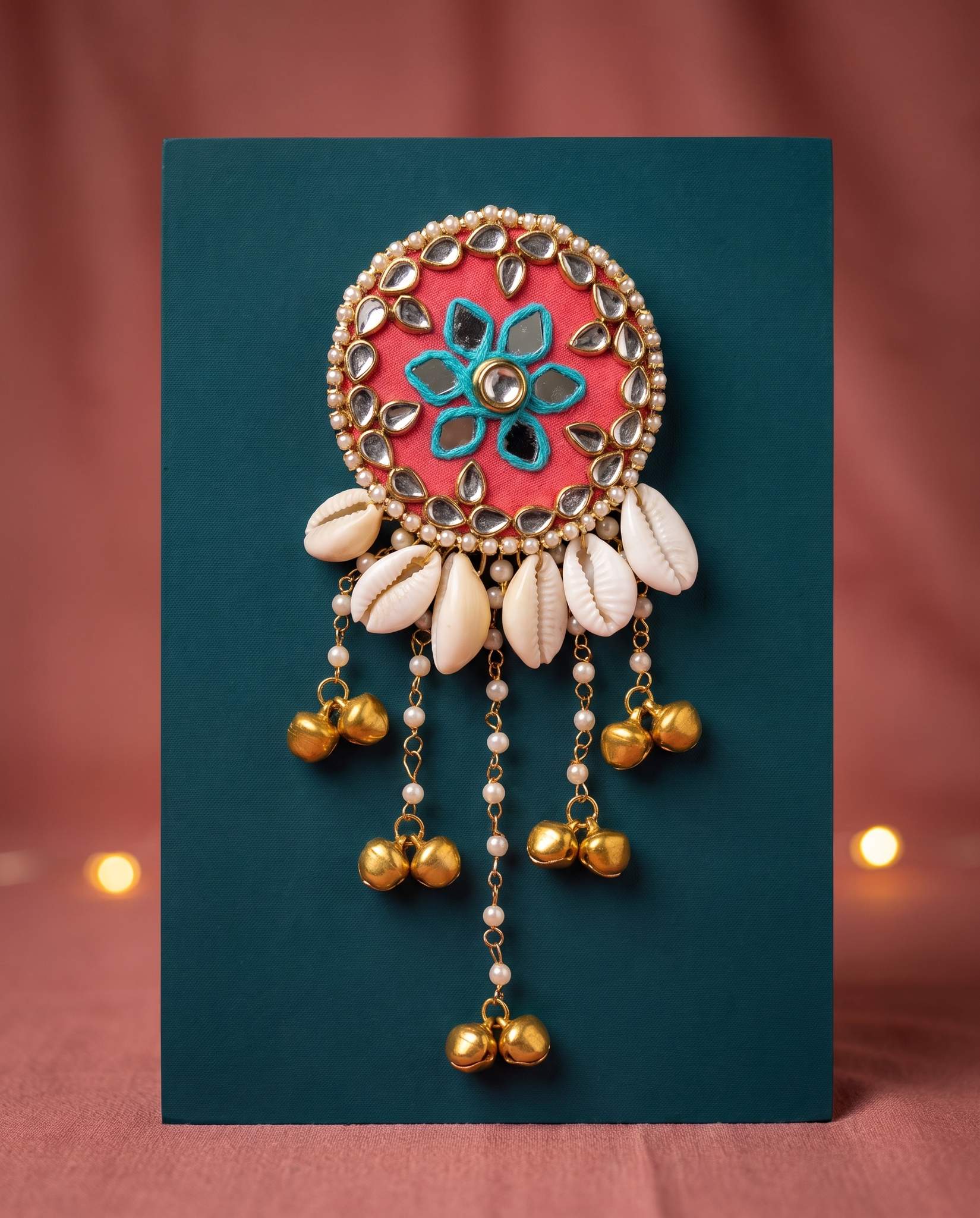 Coral mirror hair brooch displayed against teal backdrop with warm candlelight