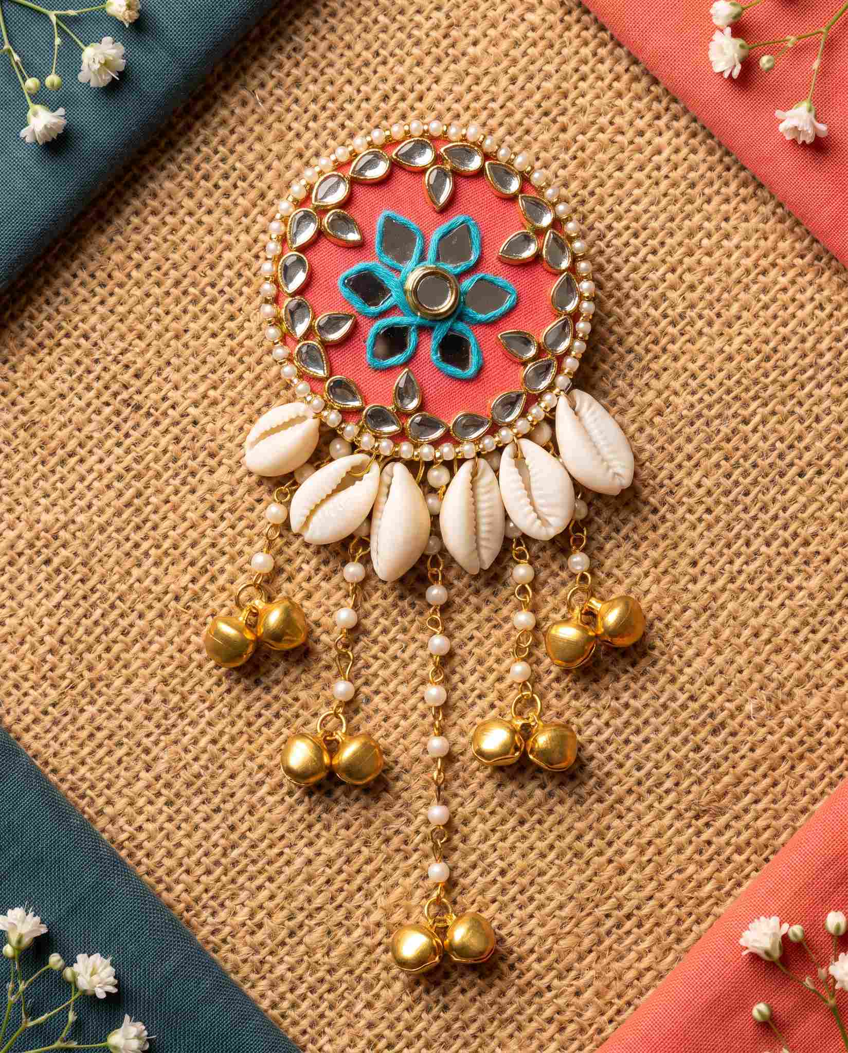 Coral mirror hair brooch styled on jute mat with teal and coral fabric corners