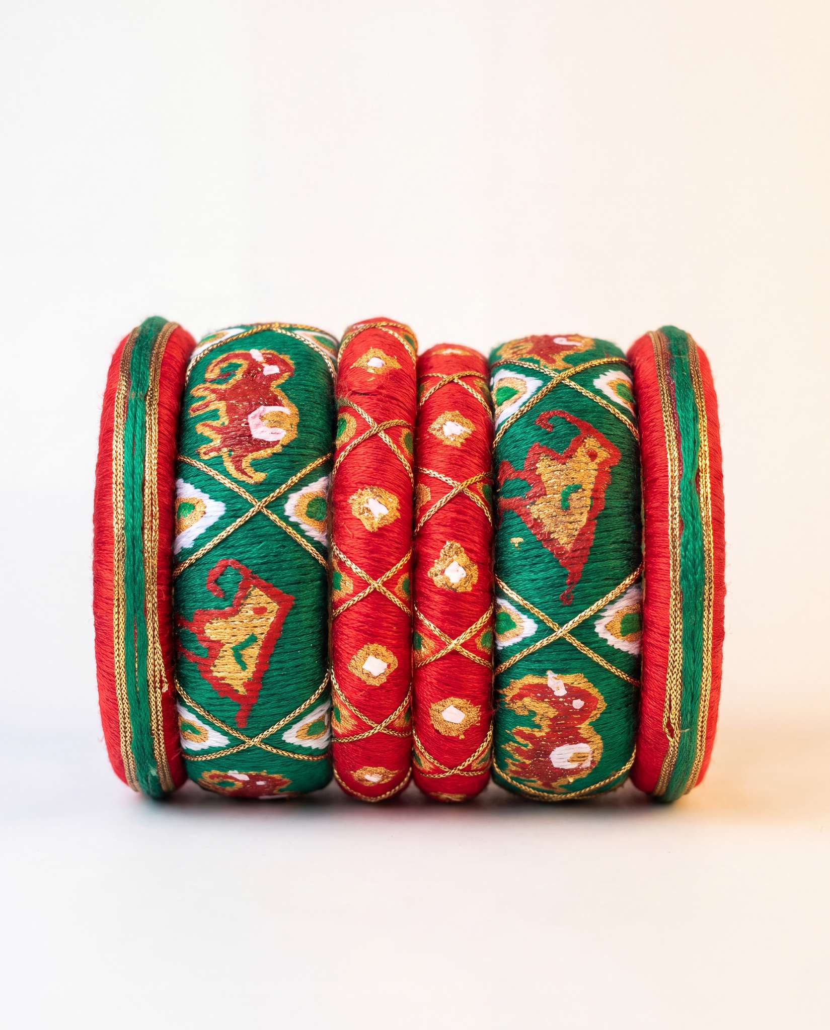 Red and green silk thread bangle set with embroidered elephant motif on plain background