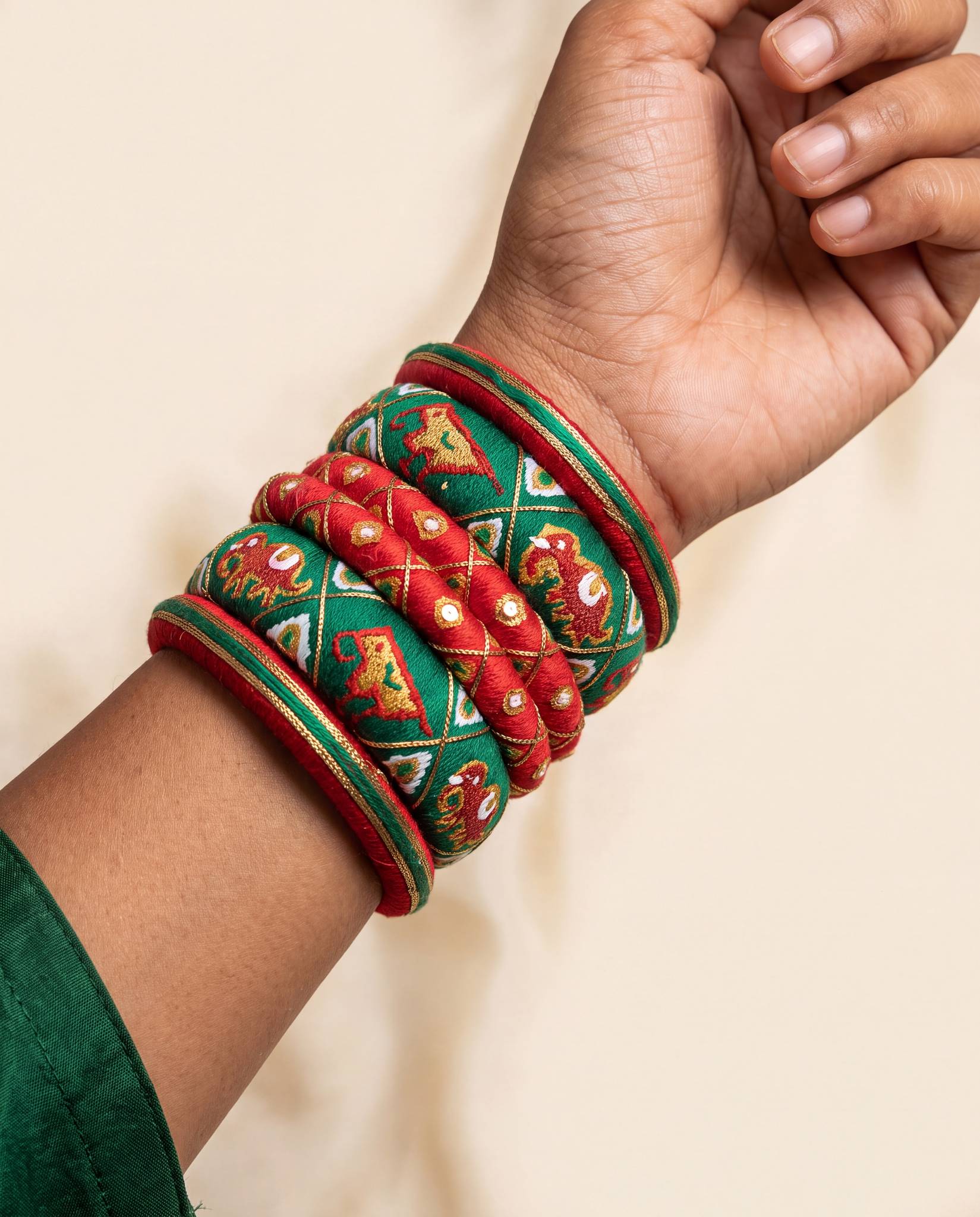 Close angle of red and green elephant motif bangles worn on wrist