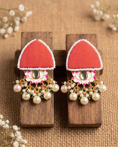 Pair of red floral earrings with pearl drops displayed on wood blocks