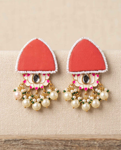 Red fabric floral earrings with pearl tassels on plain beige background