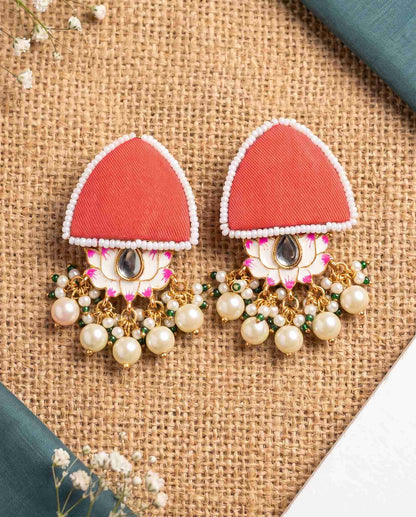 Red pearl floral earrings styled on jute mat with teal fabric