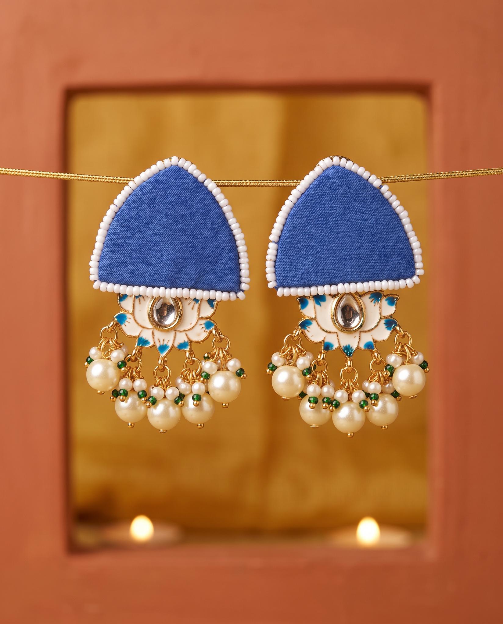 Royal blue pearl floral earrings displayed in gold mirror frame with candlelight