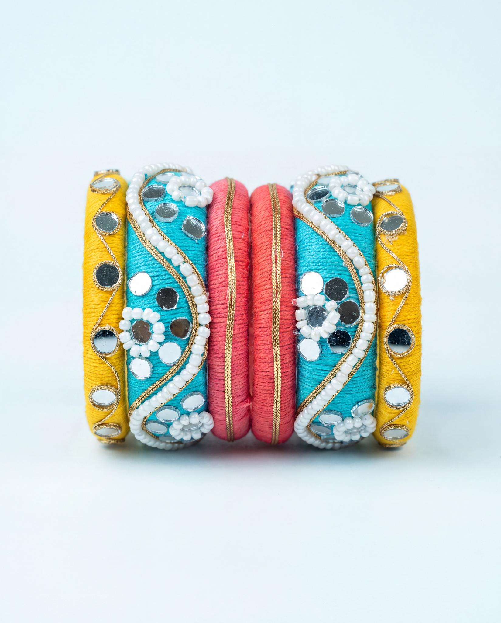 Turquoise, yellow, and pink silk thread bangle set with mirror and pearl beadwork on plain background
