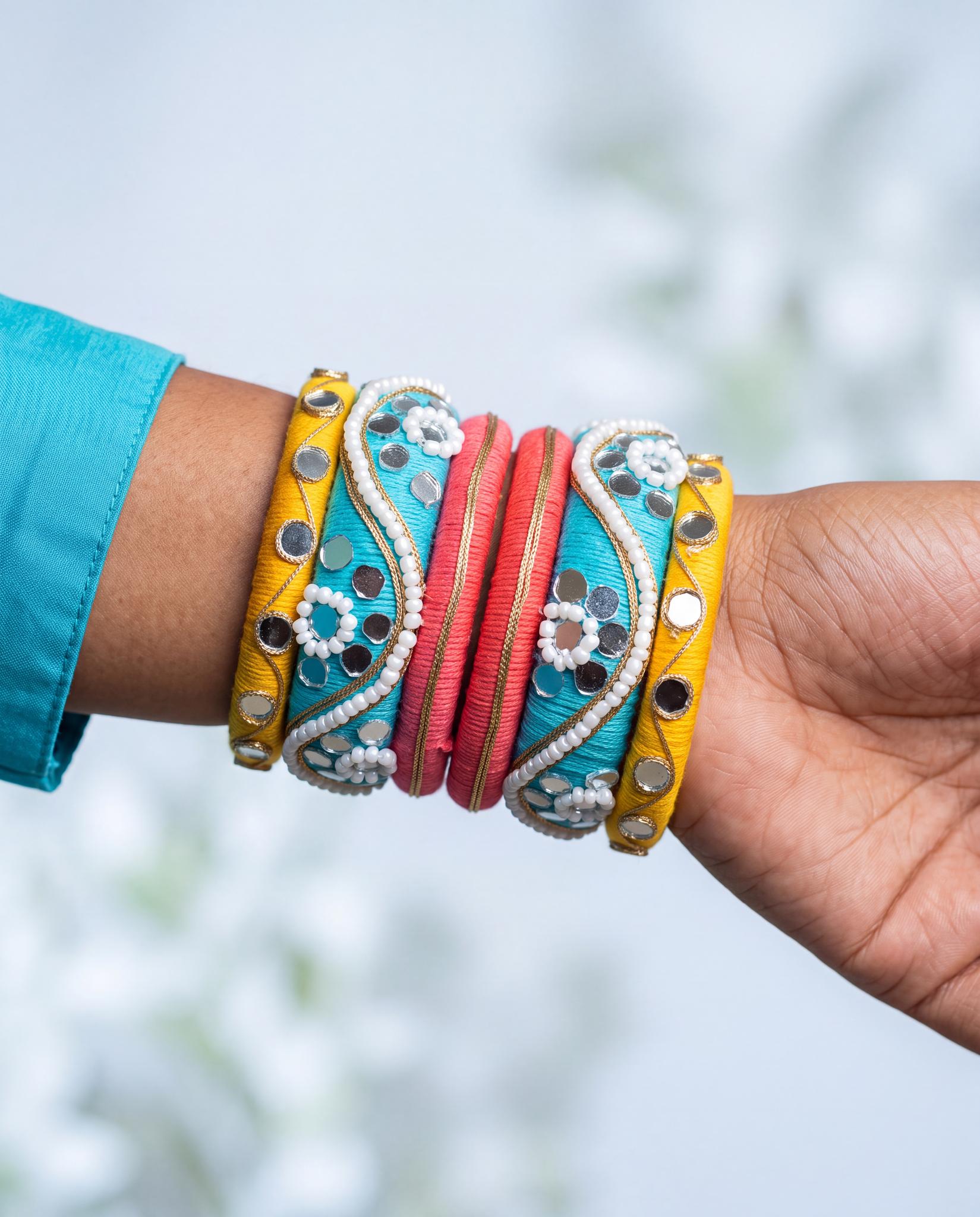 Woman wearing turquoise, yellow, and pink mirror beadwork silk thread bangles stacked on wrist