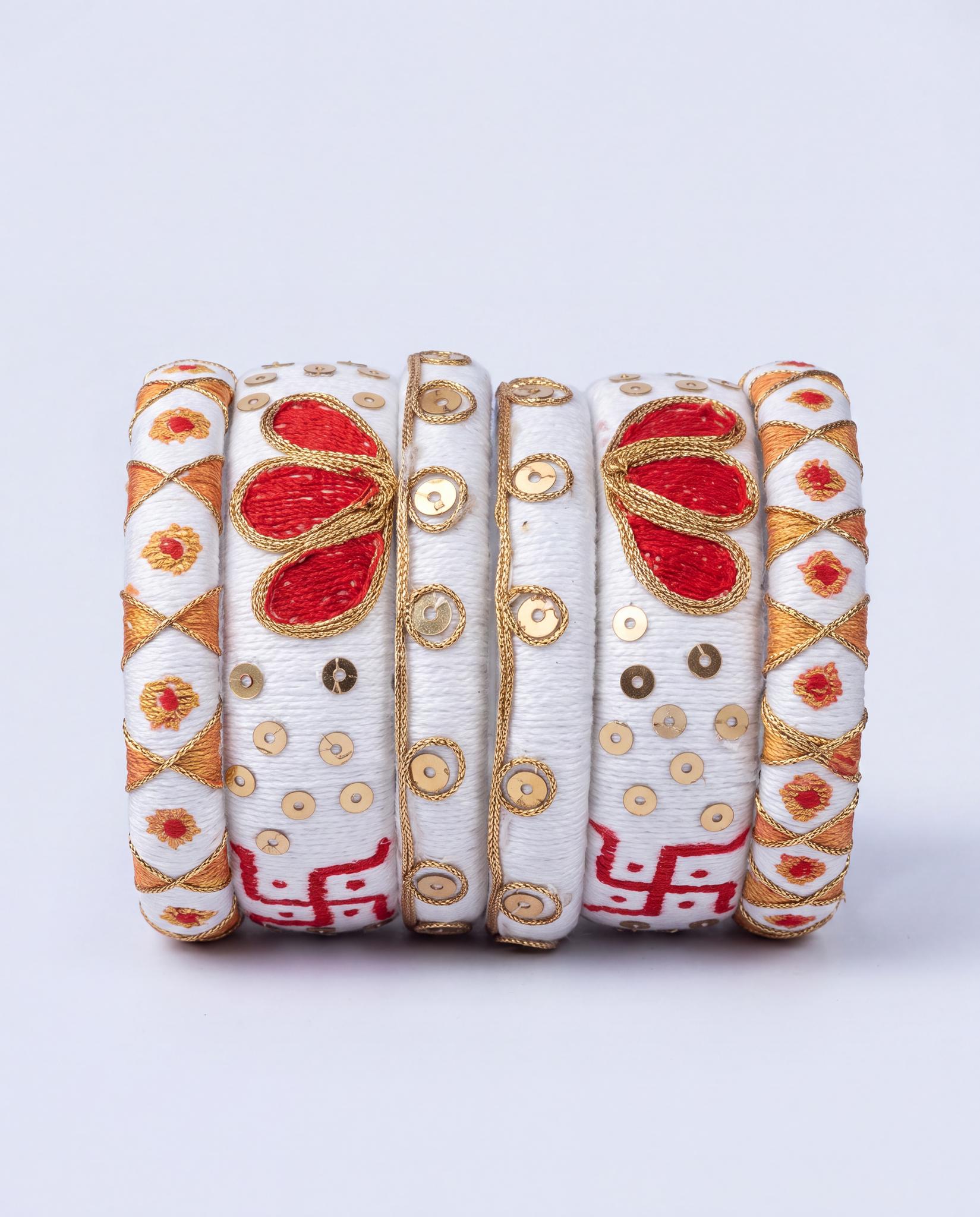 White silk thread bangle set with red floral embroidery, gold sequins, and swastik motif